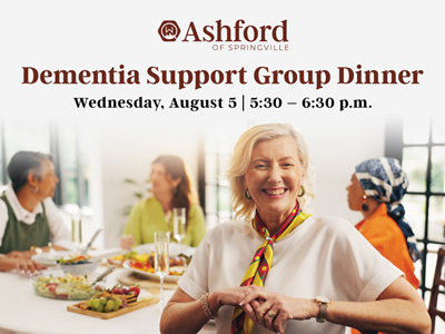 Smiling older woman sits at a dinner table with three others. Text above advertises Ashford of Springville Dementia Support Group Dinner, August 5, 5:30–6:30 p.m.